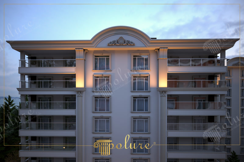 Büyük binanın ön yüzünde uygulanan kıvrımlı çatı tacı ile birlikte pencereleri saran yivli pilaster profiller ve beyaz söve süslemeleri.