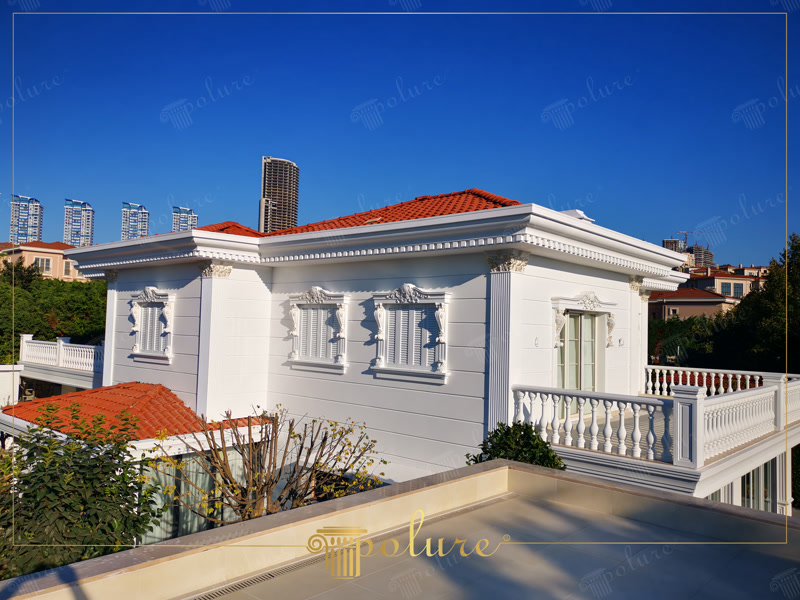 Derzli panel, pencere sövesi ve yivli pilaster sütunlarla süslenmiş beyaz renkli lüks villa dış cephesi.