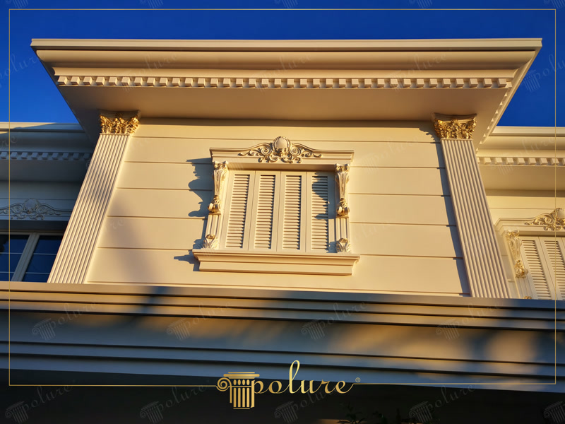 Çok katmanlı beyaz pencere sövesi, motifli taç ve altın detaylı pilaster sütunlardan oluşan lüks villa dış cephesi.