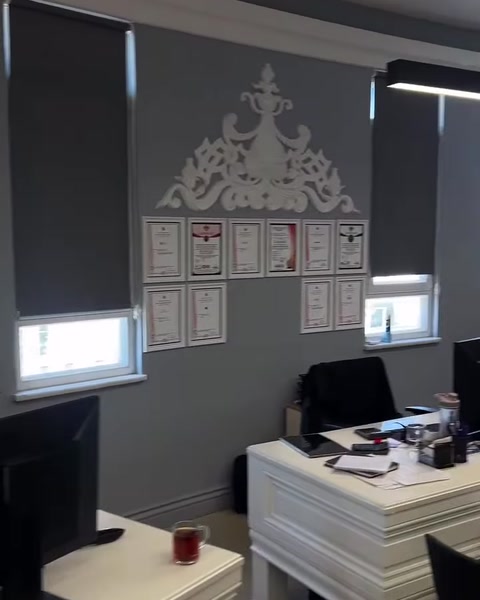 Ofis duvarında kabartmalı klasik motif ve çerçeveli belgeler bulunuyor