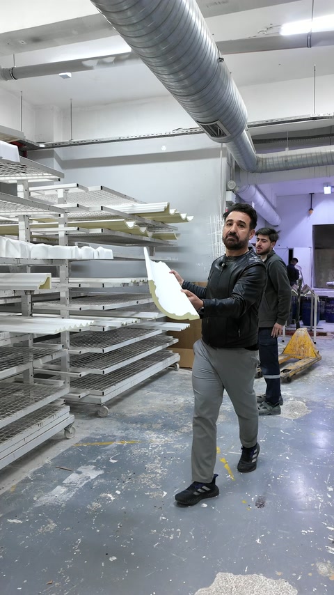 Kıvrımlı beyaz dekoratif parça üretim raflarının önünde inceleniyor