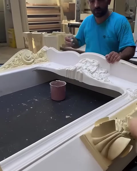 Usta, geniş çalışma tezgâhında şömine üst parçasını kontrol ediyor.