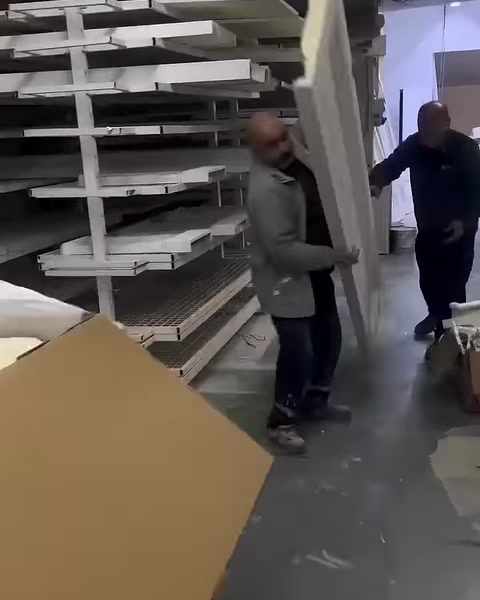 Uzun beyaz dekoratif profil atölyedeki rafların önünde taşınıyor