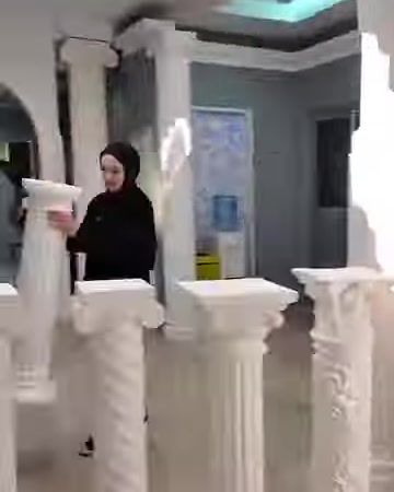 Sunucu, sade gövdeli küçük beyaz sehpayı elinde gösteriyor