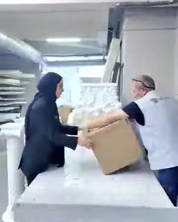 İki çalışan beyaz dekoratif parçaları kutu içinde düzenliyor