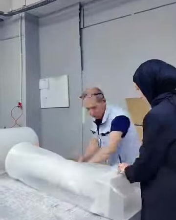 Çalışanlar büyük dekoratif ürünü paketleme masasında birlikte sarıyor