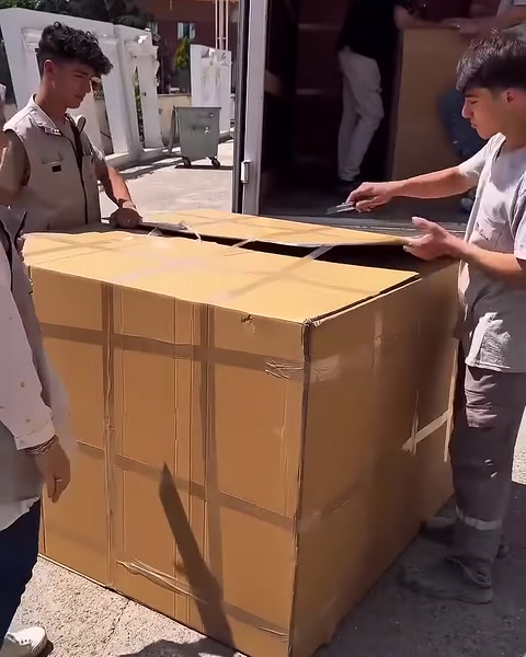 Ekip, bantları açılan büyük kutunun üst kapaklarını kaldırıyor.
