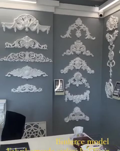 Duvarda farklı boyutlarda simetrik kabartma süs koleksiyonu sergileniyor.