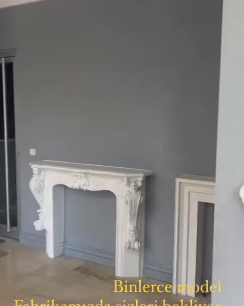 Gri duvar önünde klasik şömine çerçevesi ve panel bulunuyor.